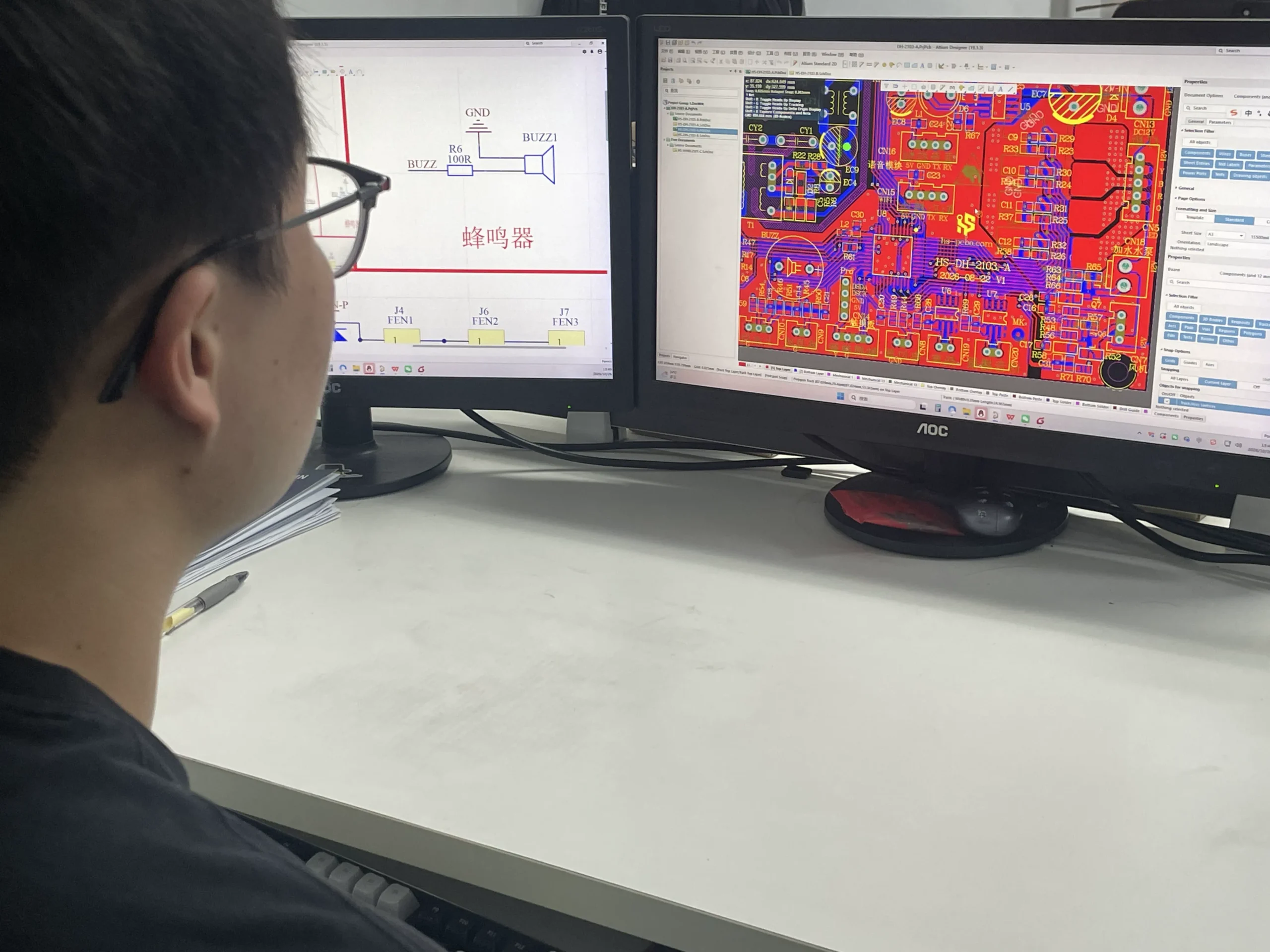 PCB design workstation with schematic and multi-layer layout on dual monitors