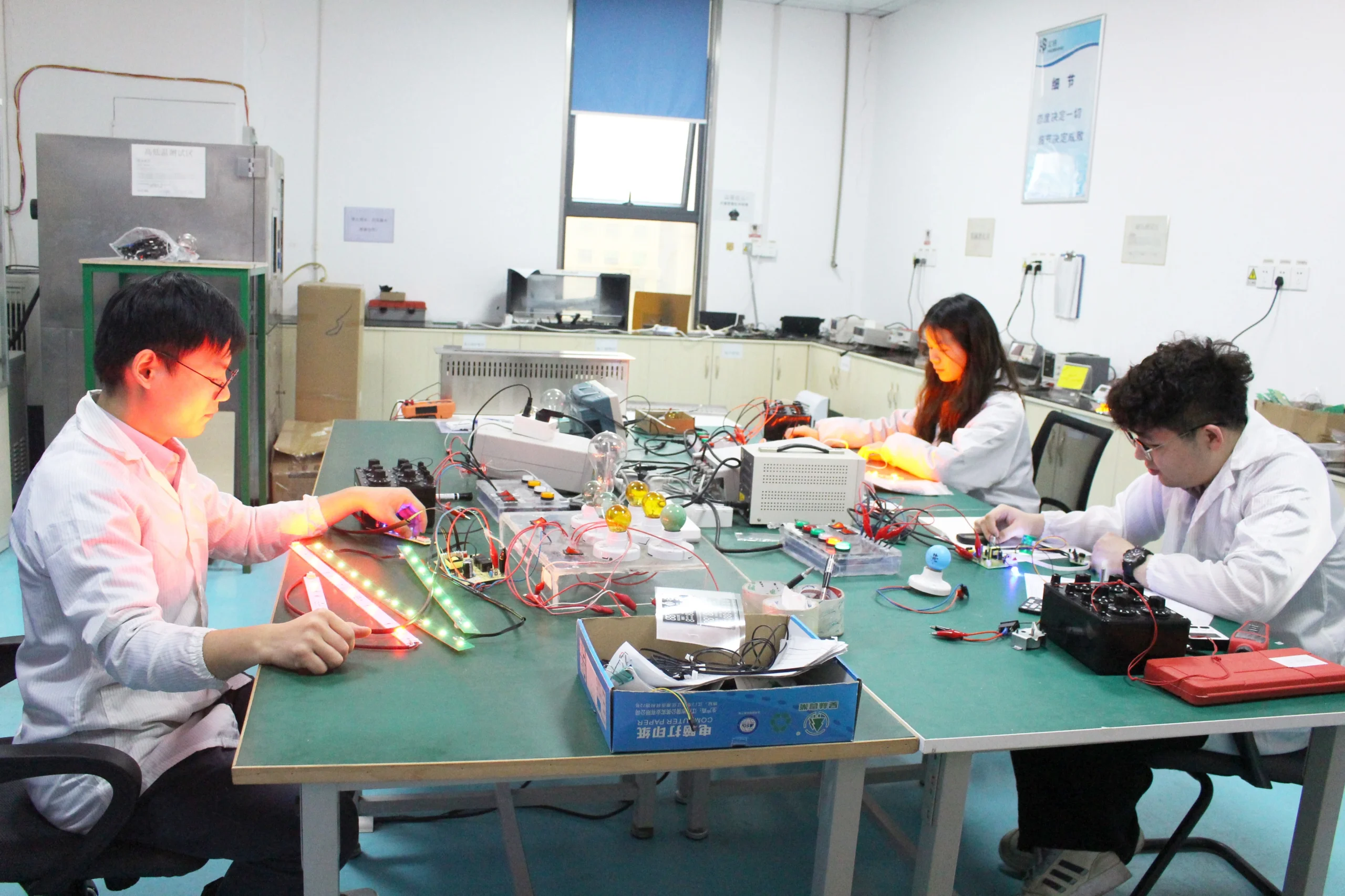 R&D engineering team reviewing a printed circuit board in the lab