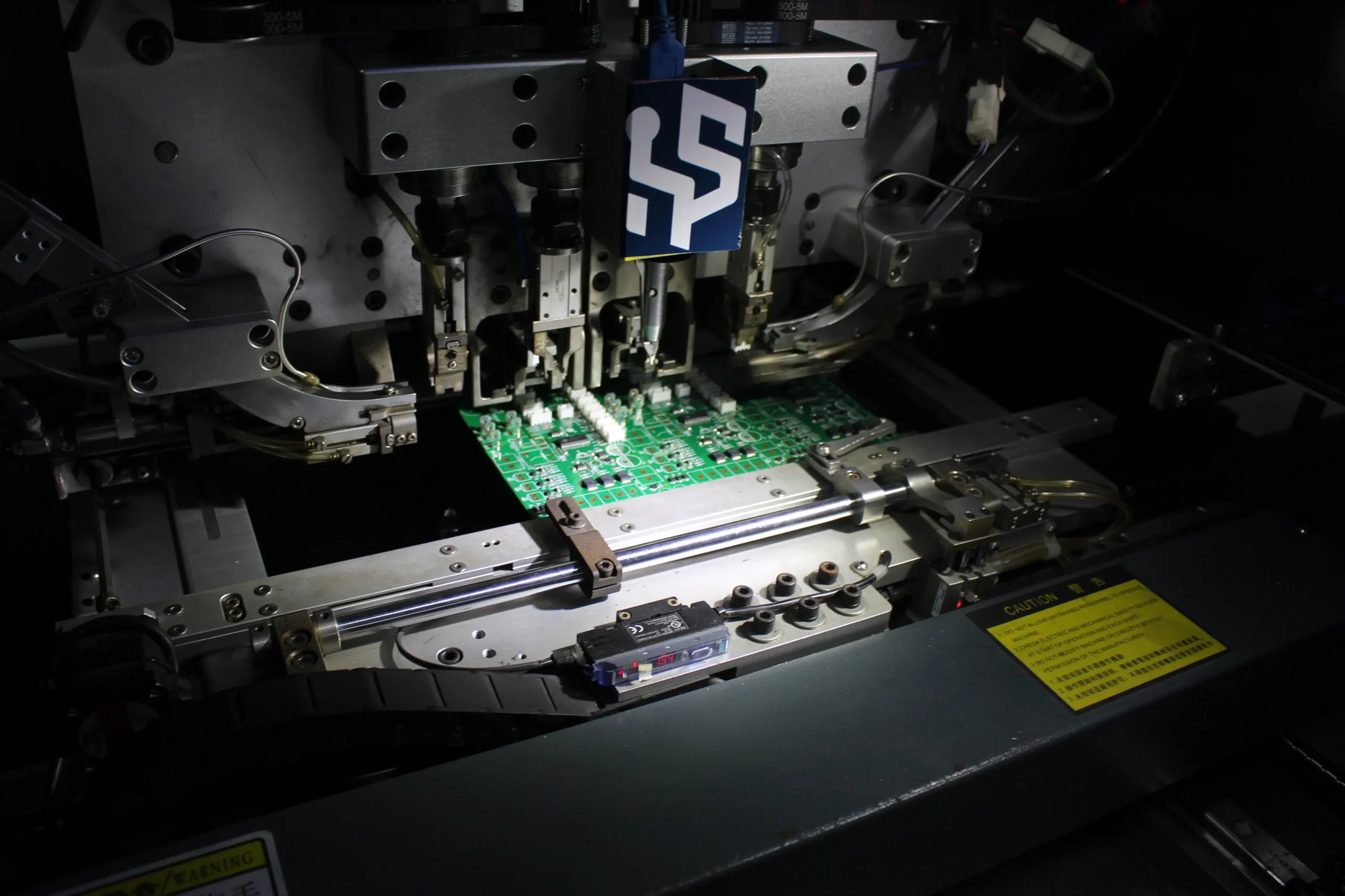 Pick-and-place head mounting a component onto a green PCBA